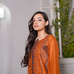 Stylish woman in traditional orange dress posing indoors with a white background.