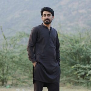 Portrait of a young man in traditional black attire standing outdoors in Rawal, Punjab, Pakistan.